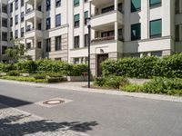 there is an empty sidewalk by the apartment block on a sunny days are so nice