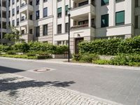 there is an empty sidewalk by the apartment block on a sunny days are so nice