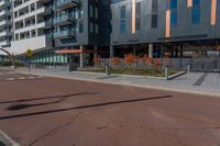 the empty street of the modern urban business district by an apartment complex and sidewalk with multiple red, orange - brick tiles