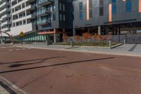 the empty street of the modern urban business district by an apartment complex and sidewalk with multiple red, orange - brick tiles