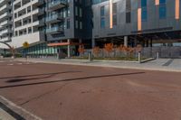 the empty street of the modern urban business district by an apartment complex and sidewalk with multiple red, orange - brick tiles