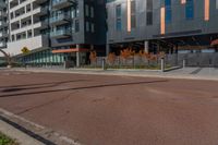 the empty street of the modern urban business district by an apartment complex and sidewalk with multiple red, orange - brick tiles