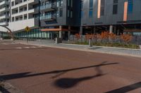 the empty street of the modern urban business district by an apartment complex and sidewalk with multiple red, orange - brick tiles