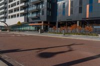 the empty street of the modern urban business district by an apartment complex and sidewalk with multiple red, orange - brick tiles