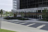 a road near a building with windows and grass on the ground and a green field