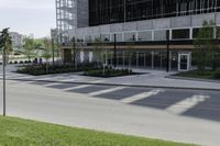 a road near a building with windows and grass on the ground and a green field