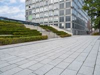 an outdoor park with steps leading to the office buildings and green plants in between them