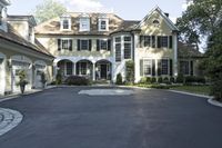 a driveway is lined with a driveway leading to an enormous house with black shuttered windows