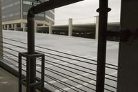 a fence with wires running along the rails near building construction area with gray sky and grey floor