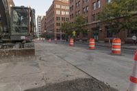 construction equipment sitting on top of a street near tall buildings on a city sidewalk,