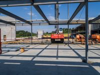 construction equipment in a large, concrete building with blue skies above it on a sunny day