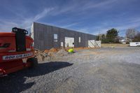 the back view of a house construction site with truck parked outside it and trucks in the parking lot