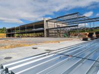 a building being constructed and covered with metal slats in front of a blue sky