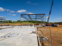 a large construction site and some crane in the background and blue skies with white clouds