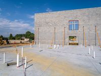 an unfinished building with white poles and pillars on it's foundation and construction cranes on the ground