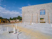 an unfinished building with white poles and pillars on it's foundation and construction cranes on the ground