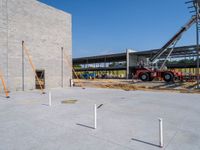 a crane is lifting concrete blocks and cement poles for the facade of a building, under construction