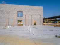 the concrete block building is being constructed, and several pillars are placed near it to indicate the progress of construction