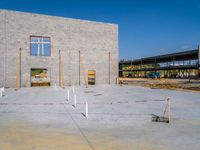 the concrete block building is being constructed, and several pillars are placed near it to indicate the progress of construction