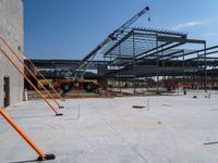 an open, industrial steel structure under construction in the sun with workers standing around it