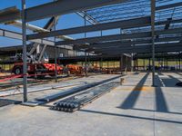 a large warehouse with construction equipment in the foreground, with a crane, and another work being carried on top