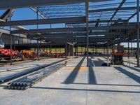 a large warehouse with construction equipment in the foreground, with a crane, and another work being carried on top