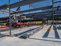 a large warehouse with construction equipment in the foreground, with a crane, and another work being carried on top