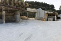 sand being turned to sand by the truck as it drives around a building structure with a covered roof