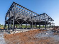 a picture of a building being built on a field near a forest in the background