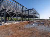 a picture of a building being built on a field near a forest in the background