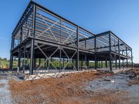 a picture of a building being built on a field near a forest in the background