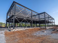 a picture of a building being built on a field near a forest in the background