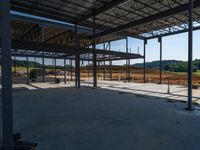 the inside of a construction site with steel beams, a steel roof and dirt on the ground