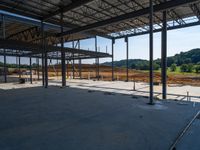 the inside of a construction site with steel beams, a steel roof and dirt on the ground