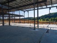 the inside of a construction site with steel beams, a steel roof and dirt on the ground