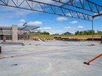 a steel frame structure stands still as construction continues on an adjacent industrial building and truck yard