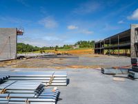 a concrete parking lot with many steel pipes and wooden beams on top of it, on a sunny day