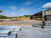 a concrete parking lot with many steel pipes and wooden beams on top of it, on a sunny day