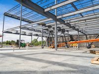 a steel structure under construction with metal beams and orange tubes on the ground in an open space