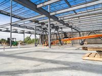 a steel structure under construction with metal beams and orange tubes on the ground in an open space