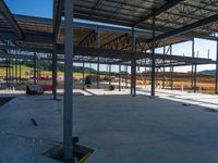 a view from behind the pillars of an unfinished warehouse building under construction with wood floors and metal roofing