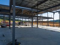 a view from behind the pillars of an unfinished warehouse building under construction with wood floors and metal roofing