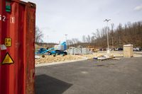 a small crane next to a container full of items near some buildings and an airport