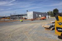 construction work in progress at an open lot on a sunny day, with machinery parked outside