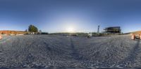 a 360 - ball lens of construction work with sun reflecting in back ground and buildings and road work