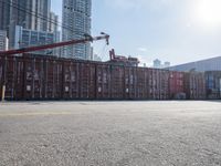 a construction worker stands near container boxes outside a building area with other containers in the background