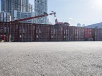 a construction worker stands near container boxes outside a building area with other containers in the background