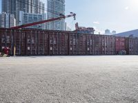 a construction worker stands near container boxes outside a building area with other containers in the background