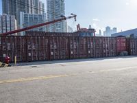 a construction worker stands near container boxes outside a building area with other containers in the background