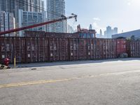 a construction worker stands near container boxes outside a building area with other containers in the background